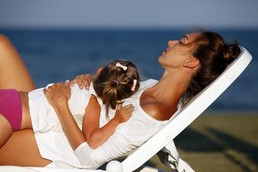 Happy mother holding her daughter on the beach