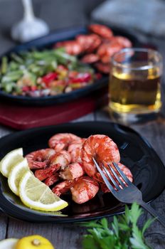 Grilled prawns with lemon, vegetables and beer. Rustic, low key and bokeh.