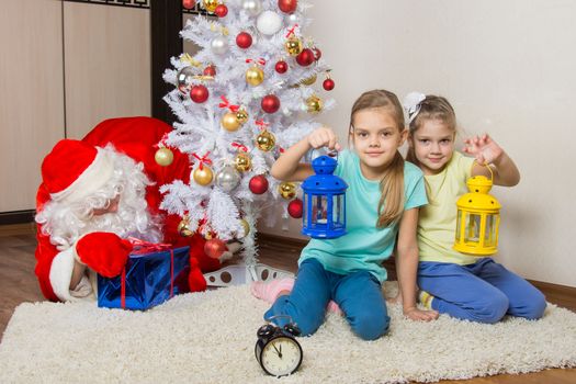 Two girls with flashlights waiting for Santa Claus at the Christmas tree in New Years Eve