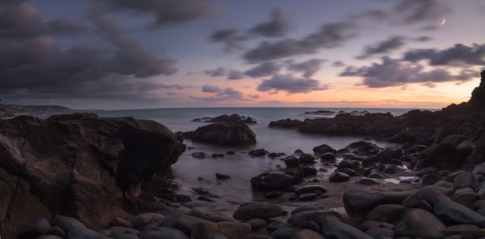 Moonset and sunset at Crescent Bay beach in Laguna Beach, California, United States