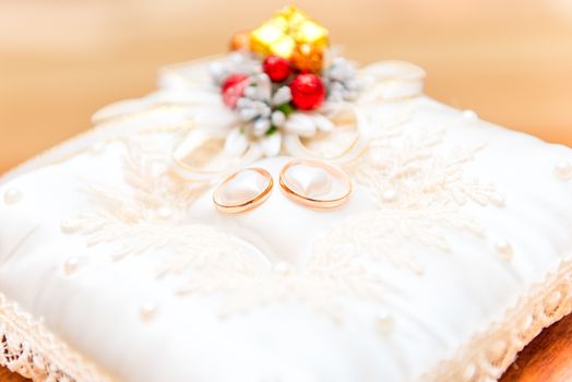 pair of gold wedding rings on a beautiful pillow close up