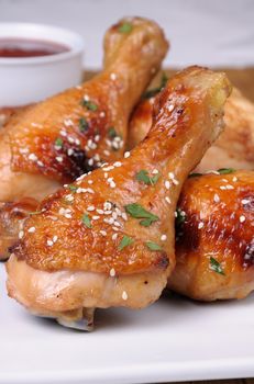 Fried chicken leg with sesame seeds in a plate and sauce closeup     