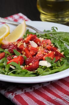 Salad of arugula and strawberries with crushed peanuts, almonds