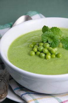 A plate of soup puree of green peas with mint on a table