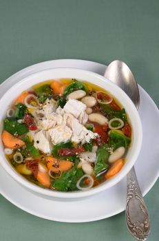 chicken soup with beans, spinach, tomatoes and other vegetables