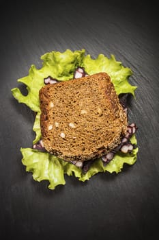 sandwich with sausage and lettuce on a dark background