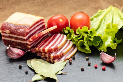slices of sausage with bacon on a dark background