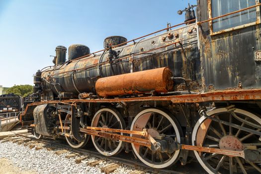 Close up detailed view of historical old rusty iron train locomotives, on blue sky background.