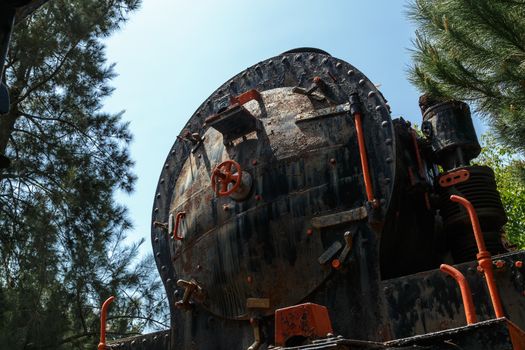 Close up detailed view of historical old rusty iron train locomotives, on blue sky background.