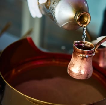 Preparation of Turkish coffee in the cezve in the sand at the cafe bar