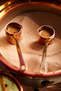 Preparation of Turkish coffee in the cezve in the sand at the cafe bar