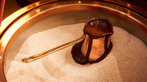 Preparation of Turkish coffee in the cezve in the sand at the cafe bar