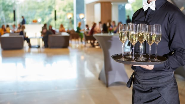 Waiter serving champagne glasses on a tray