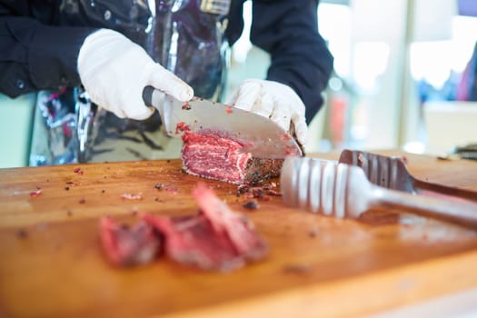 Butcher cutting slices of fresh beef. Shallow dof