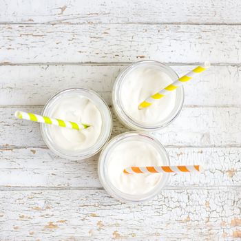 Yogurt in three small jars with straws. top view