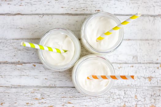 Yogurt in three small jars with straws. top view
