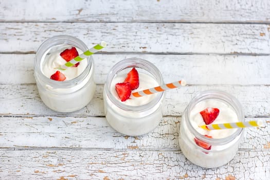 Three in a jar of yogurt with strawberries on a wooden board