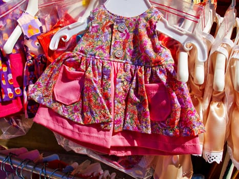 Baby girl beautiful elegant bright summer dresses on hangers in a display shop