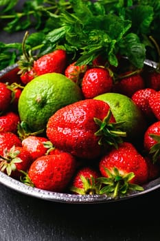 iron plate with ripe strawberry fruit and lime on a dark background