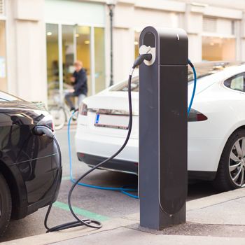 Power supply for electric car charging.  Electric car charging station. Close up of the power supply plugged into an electric car being charged.