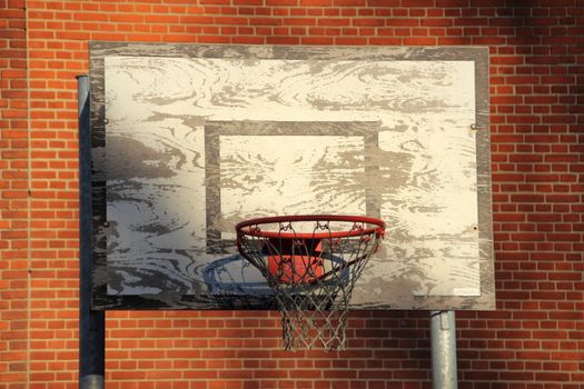 Old and worn outdoor basketball net with red brick background