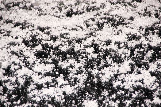 Cold white hail on a cars windshield