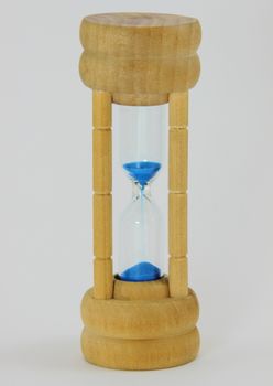 Isolated light pine hourglass with blue sand