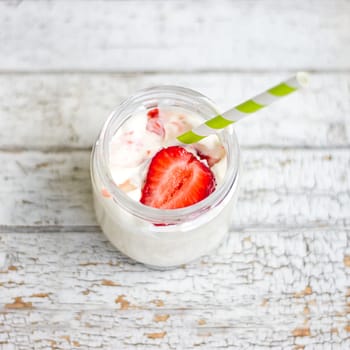 Smoothie yogurt, strawberries in glass jar on wooden background