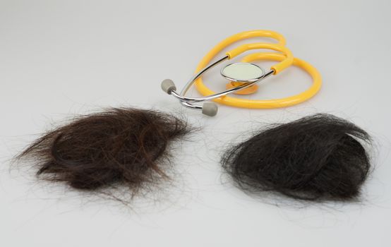 Brown and black hair loss  with stethoscope were place on white background.