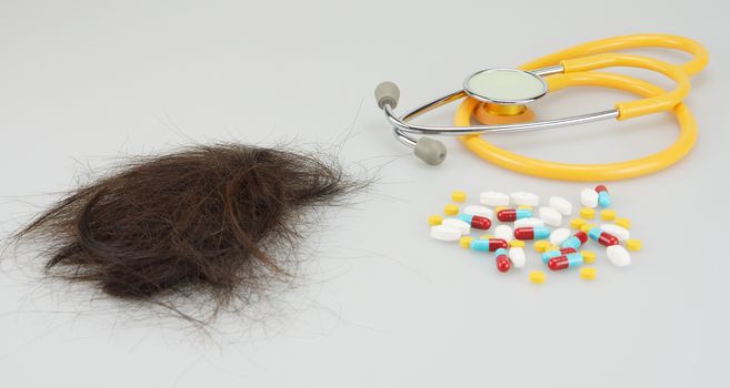 Brown lost hair with medicine and stethoscope on white background.