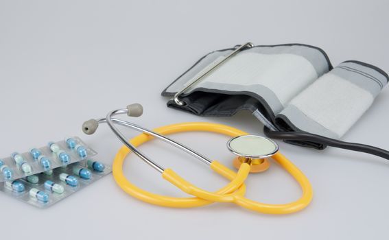 Pack of medicine with blood pressure equipment placed on white background.