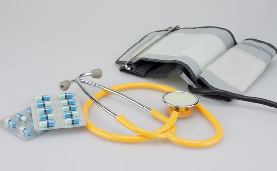 Pack of medicine and blood pressure equipment placed on white background.