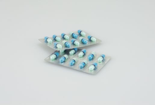 Two packing of blue medical capsules was placed on white background.