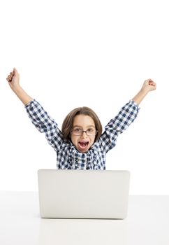 Happy little girl sitting on a desk and working with a laptop