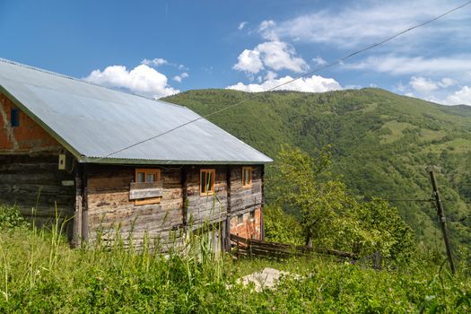 Landscape view of high mountains of Black Sea region with small mountain house and trees around, on blue sky background.
