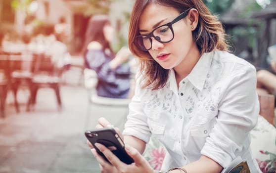 A Woman playing mobile phone in outdoor restaurants.