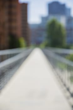 Unfocused blurred view on bridge and summer alley, in city setting. Urban environment background