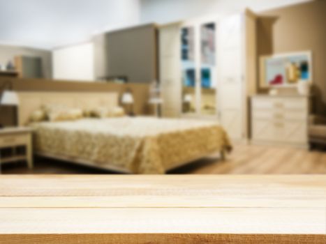 Wooden board empty table in front of blurred background. Perspective light wood over blur in modern comfortable bedroom with beige bed. Mock up for display or montage your products