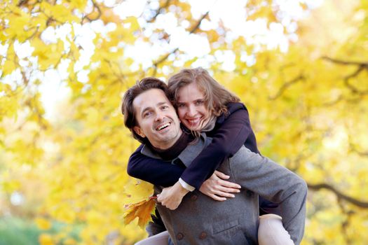 Smiling couple hugging in autumn park with yellow trees