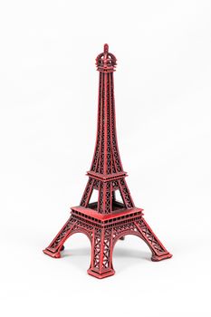 Close up shot of a red miniature model of the Eiffel Tower isolated on a white background