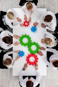 Business team sitting around the table with cogs, teamwork concept