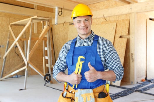 Workman with wrench inside wooden house under construction