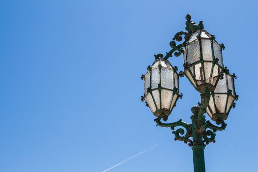 Ornate street lamp with 3 lanterns.  Capital of island Malta, Valletta. Bright blue summer sky.