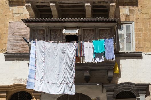 Typical traditional balcony in the capital of Malta - Valletta. Clean laundry getting dry in the sun.