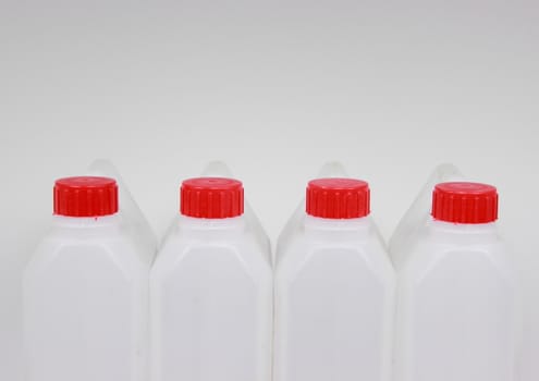Four empty jerrycans of white plastic with red lids