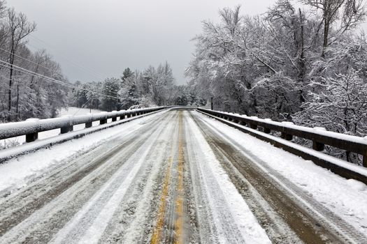 A winter landscape show snow falling on a snow drenched bridge