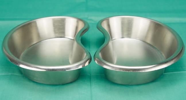 Kidney-shaped bowl, a stainless steel container, placed on green fabric in operation room.