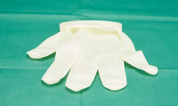 One piece of latex medical gloves placed on green fabric.