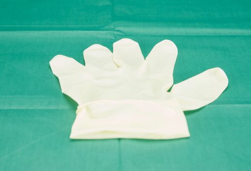 One piece of latex medical gloves placed on green fabric.