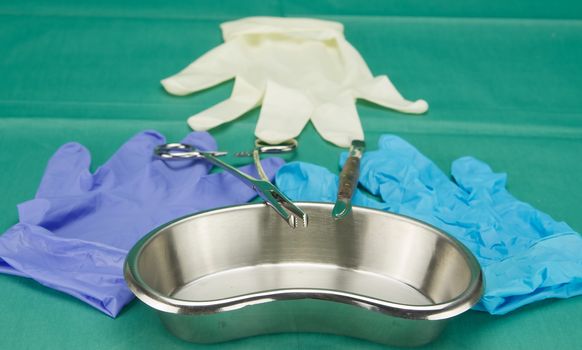 Surgical equipment on kidney bowl and three pieces of latex gloves